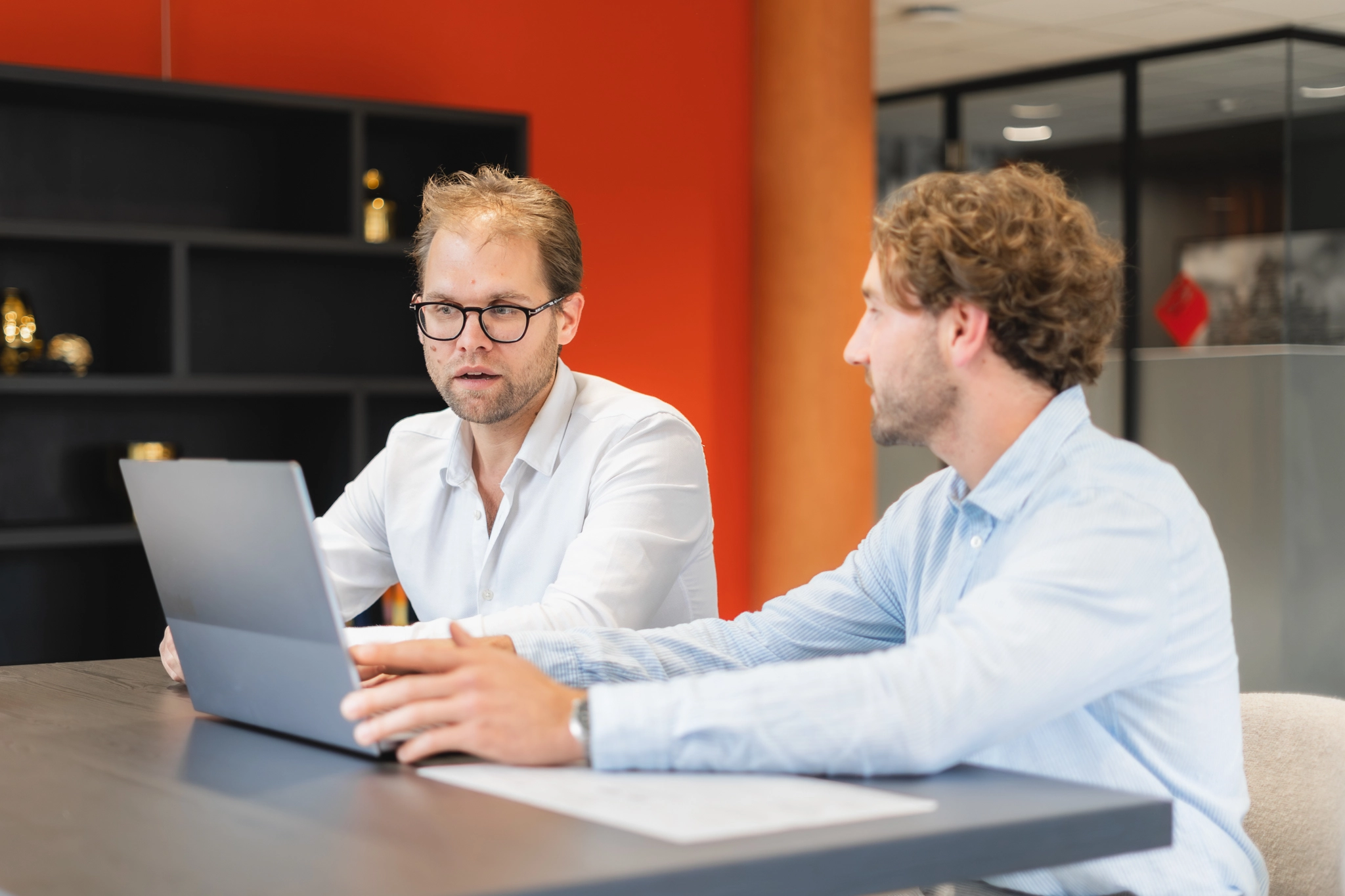 Twee mannen aan tafel achter een laptop